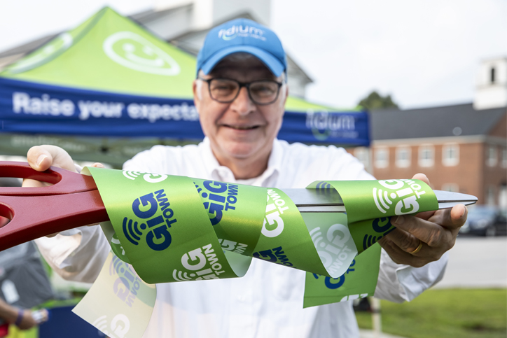 Man cutting Fidium opening ribbon